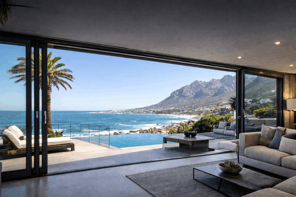 Luxury coastal home with large aluminium doors Camps Bay installation opening to an ocean-view terrace and infinity pool along the Atlantic Seaboard.